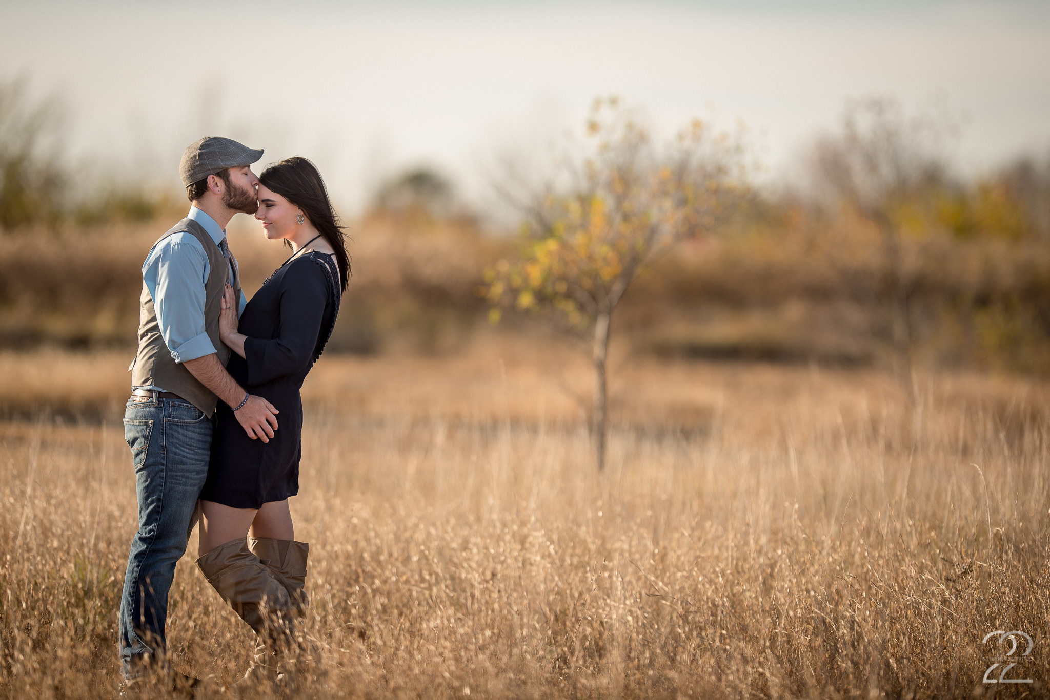 Man in jeans and vest kisses woman in dress in tall grass at Oakes Quarry Park by Dayton Wedding Photographer Studio 22 Photography